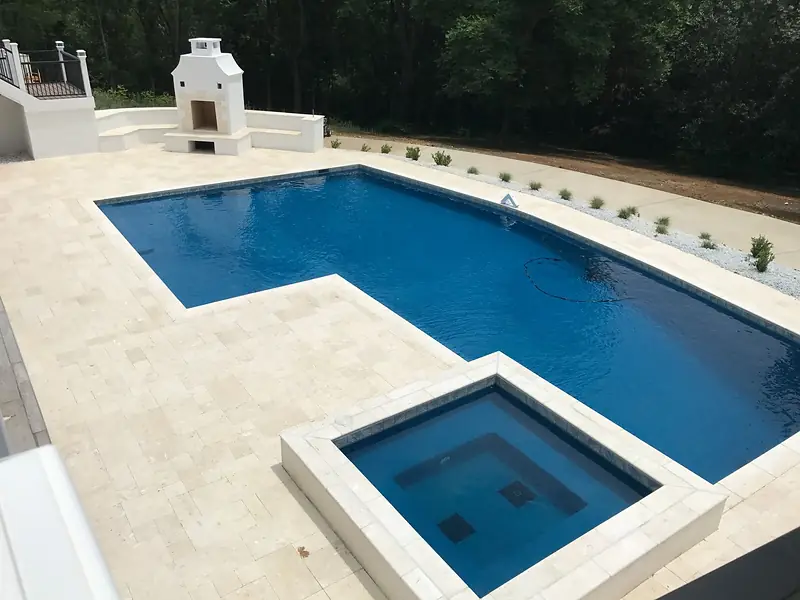 A geometric Sequoyah pool with a raised spa and a stone fireplace.