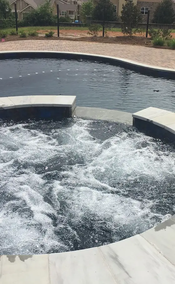 An integrated spa spilling into a Sequoyah pool, the jets running.